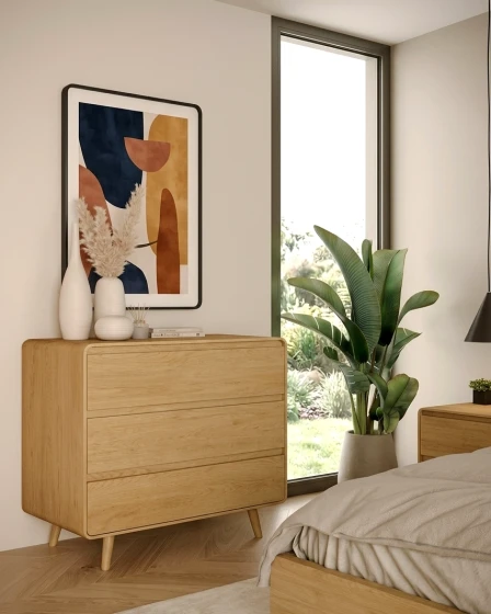 Cómoda Tivoli com pés em madeira clara junto a janela, com vaso e quadro abstrato