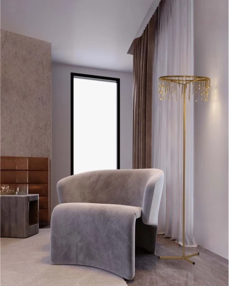 Candeeiro de pé dourado com pendentes em cristal ao lado de poltrona cinzenta