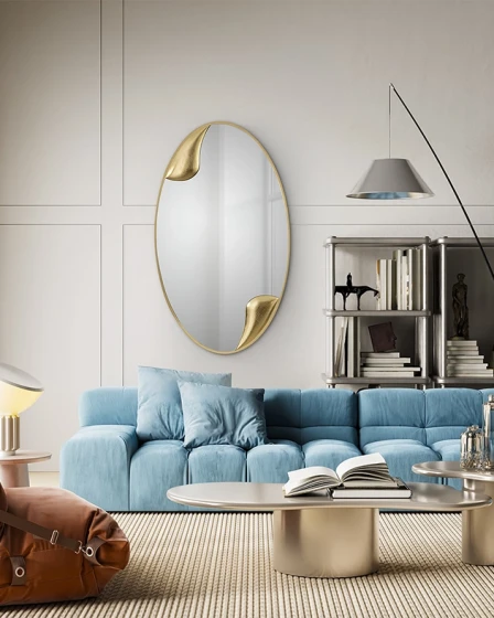 Espelho oval Daisy com apontamentos dourados sobre sofá azul em sala moderna